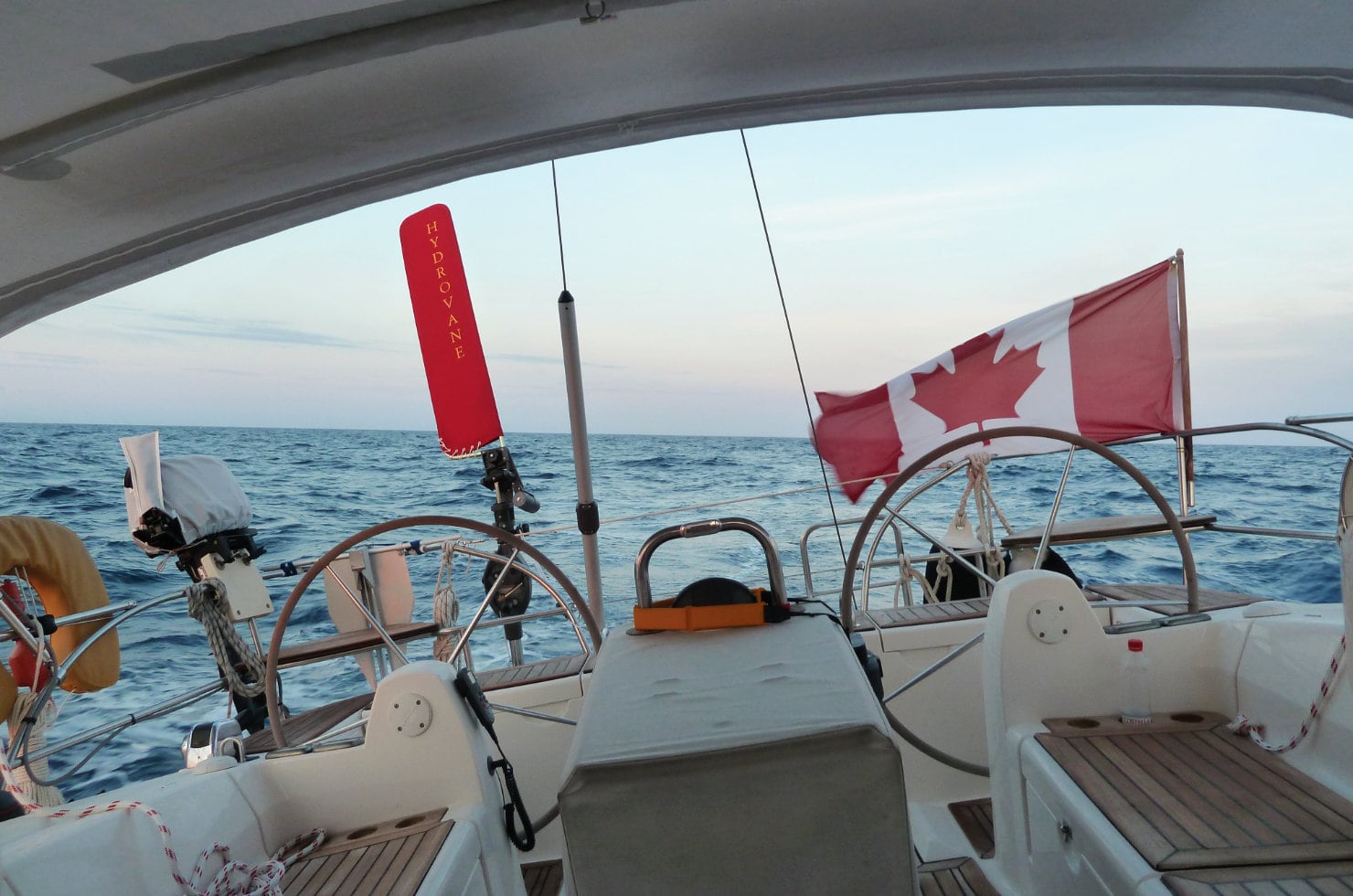 クルーザーの中から船の後ろの海を眺める写真。左にはハイドロベーンの赤いベーンが配備され右にはカナダ国旗が風にはためく
